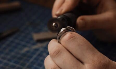person holding a silver ring and a jewelry grinder