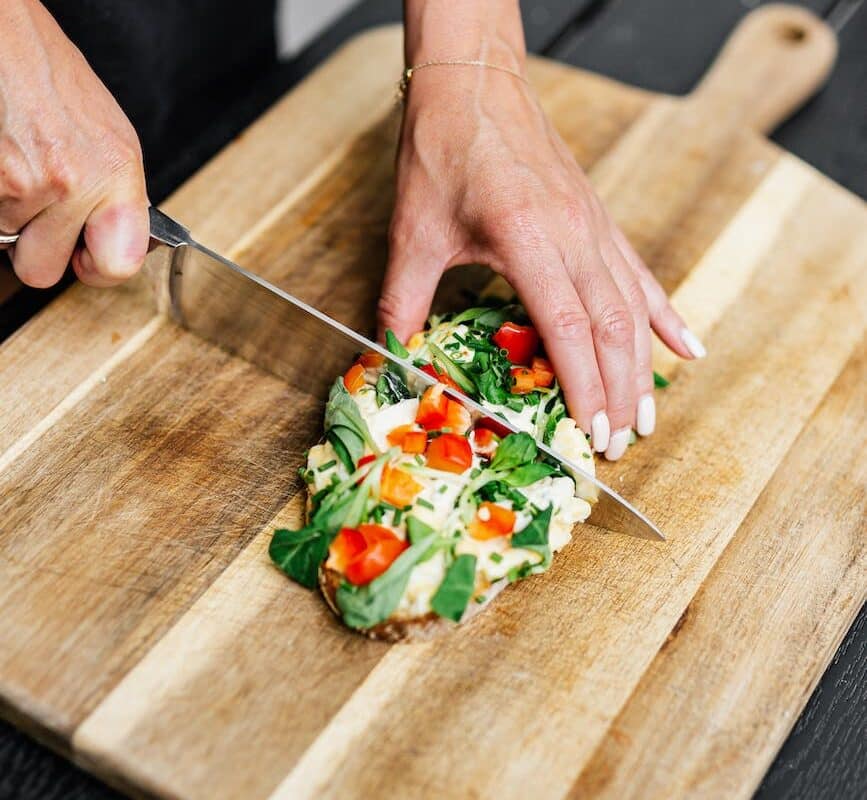 close up of woman cutting food on board