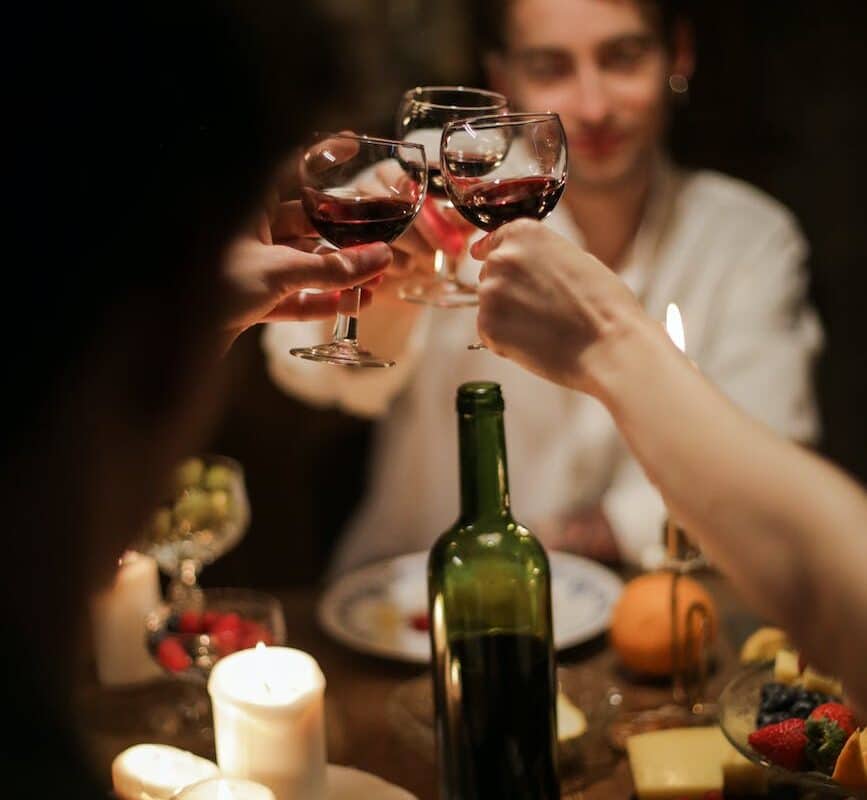 people holding wine glass with red wine