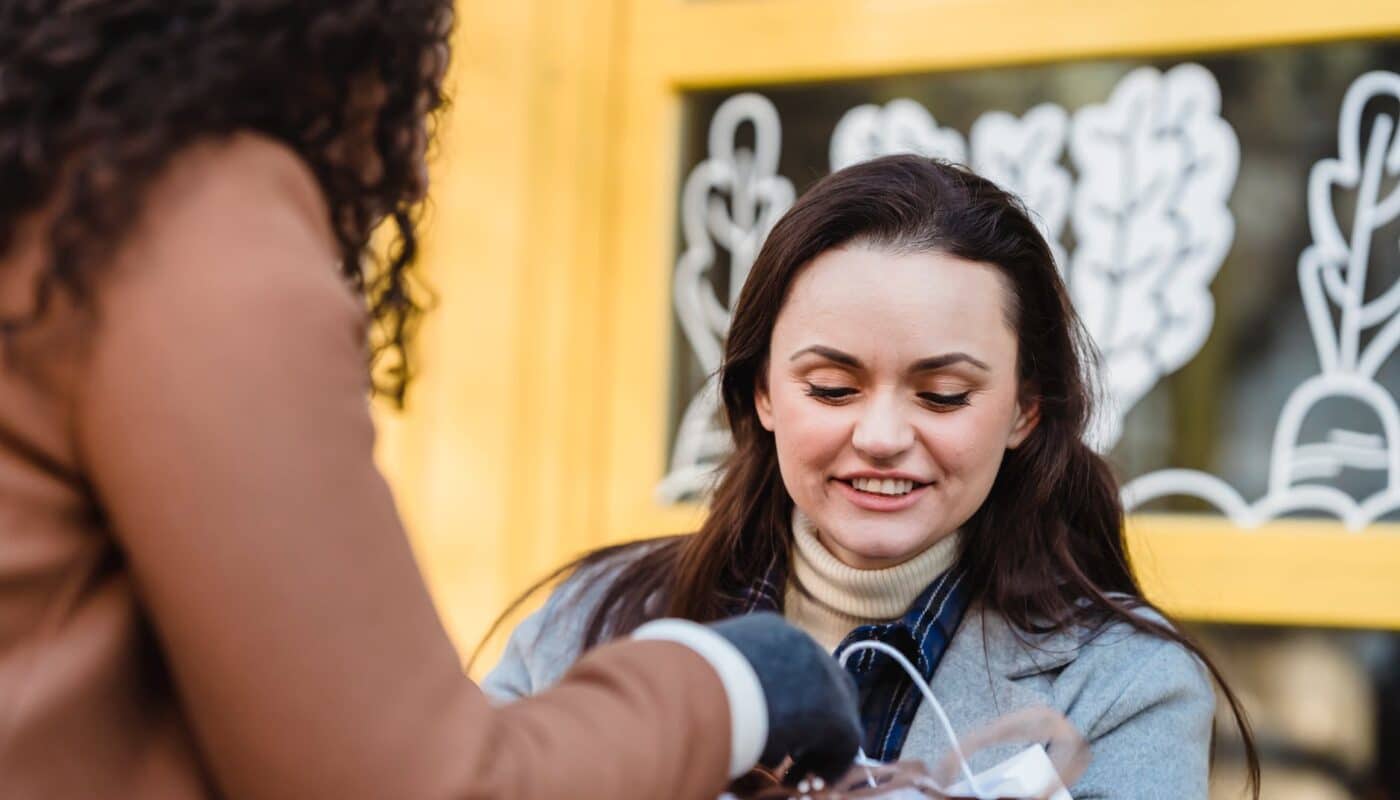 women at table checking gift packages in street near building