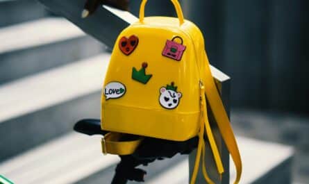 yellow backpack with five assorted stickers on grey metal stairway rail