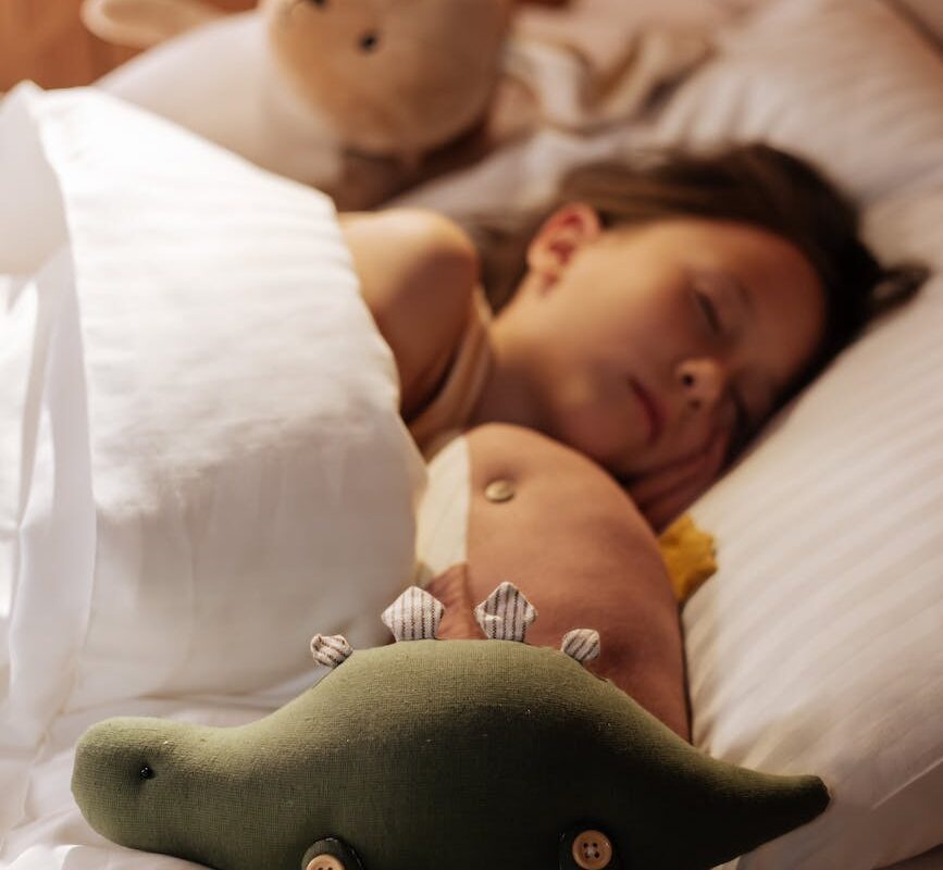 girl sleeping in bed surrounded by plush toys