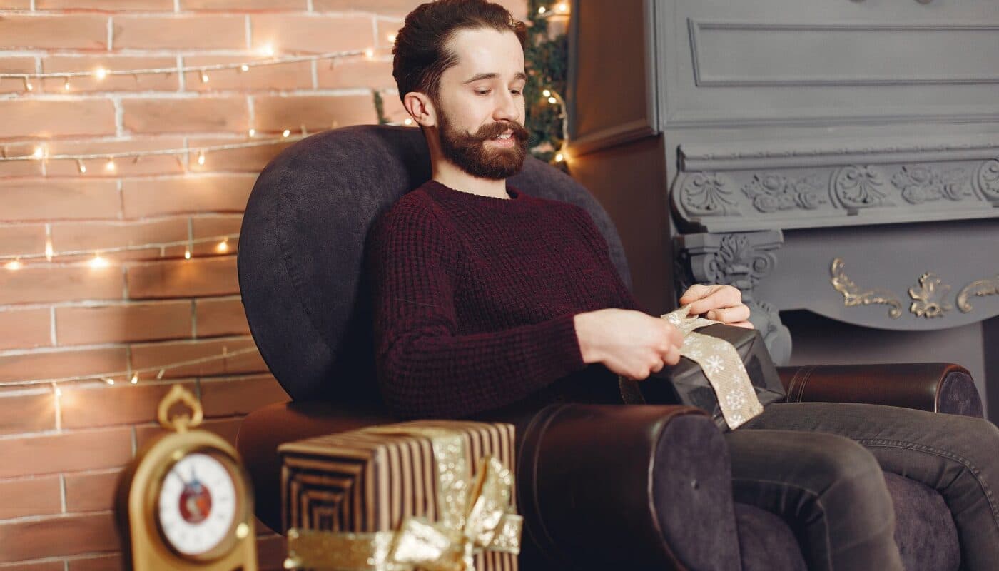 man sitting in armchair with christmas present