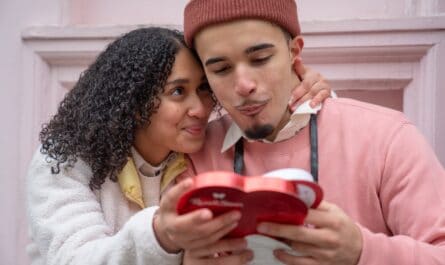 loving young hispanic couple eating chocolates on street and cuddling