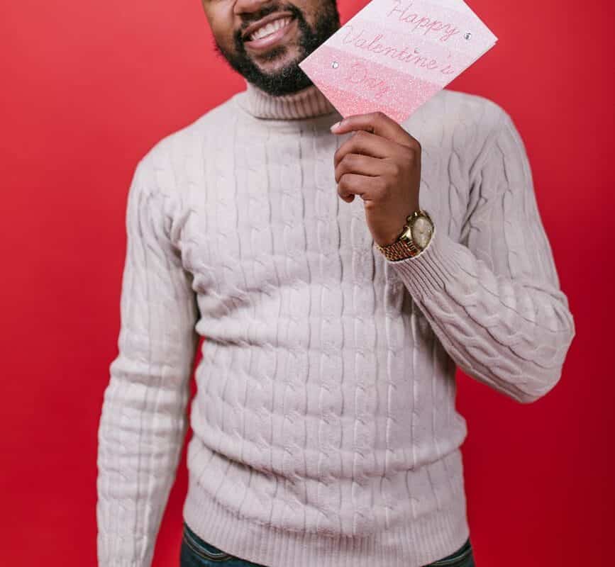 man in white sweater holding a valentine s day card
