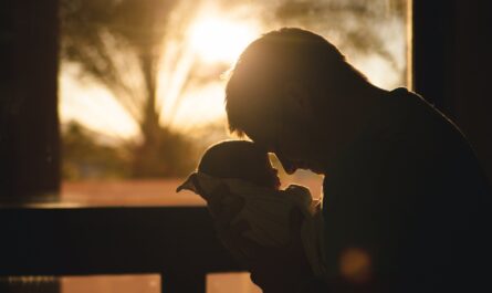 man carrying baby drawing their foreheads