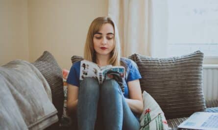 woman sitting on couch while reading a book