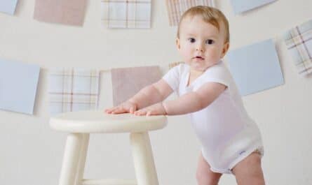 baby holding white wooden stool
