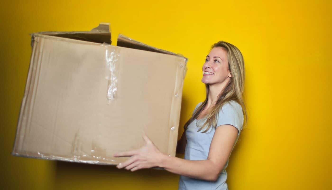 woman in grey shirt holding brown cardboard box