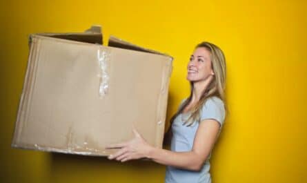 woman in grey shirt holding brown cardboard box