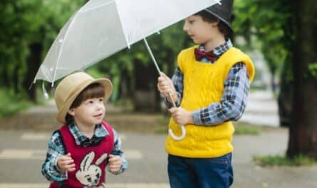 toddler holding umbrella beside girl