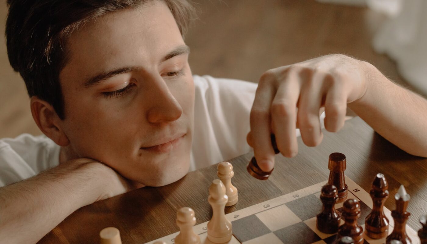 woman holding brown wooden chess piece