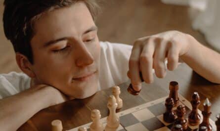 woman holding brown wooden chess piece